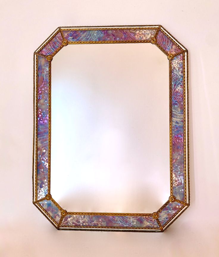 a mirror that is on the wall with an artistic design in it's center