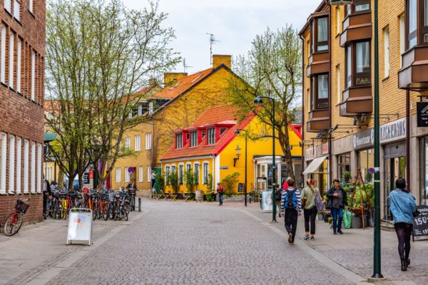 people are walking down the street in front of some buildings and bicycles parked on the sidewalk