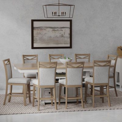 a dining room table with white chairs and a painting on the wall in the background