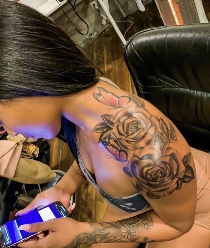 a woman with a rose tattoo on her stomach holding a cell phone and looking at it