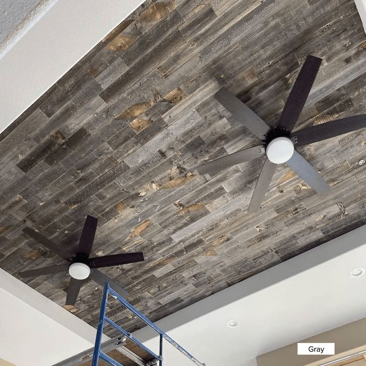 a ceiling fan mounted to the side of a wooden wall in a room with ladders