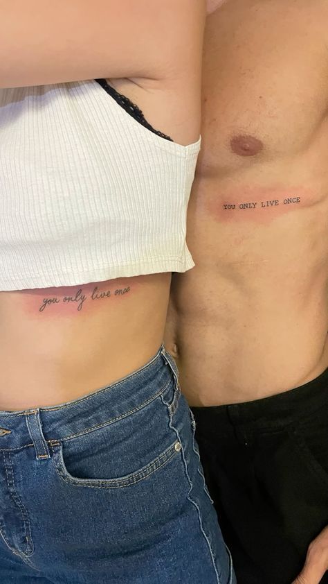 two people with small tattoos on their stomachs, one is holding the other's back