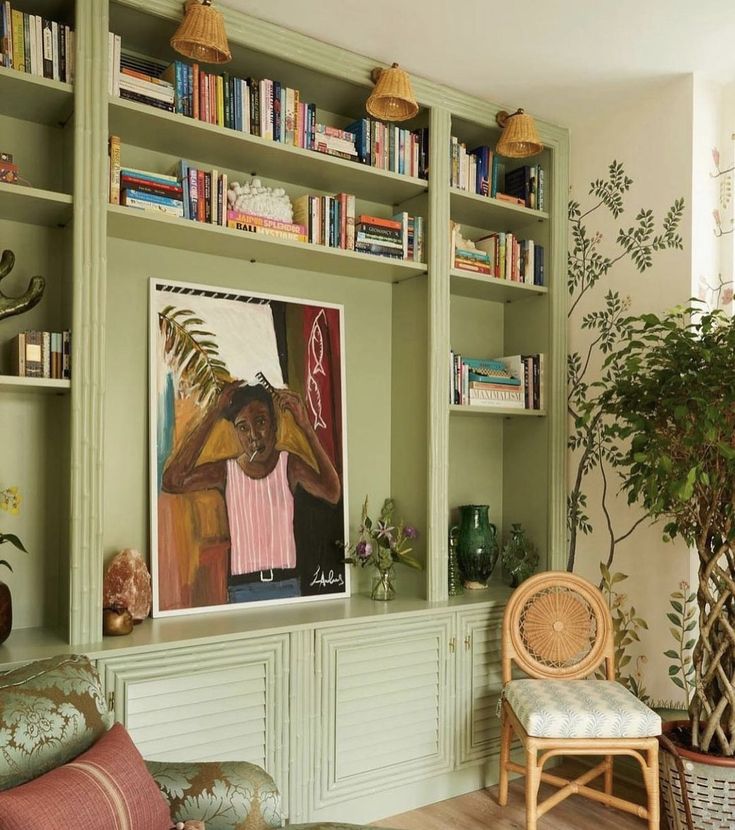 a living room filled with lots of green furniture and bookshelves next to a potted plant