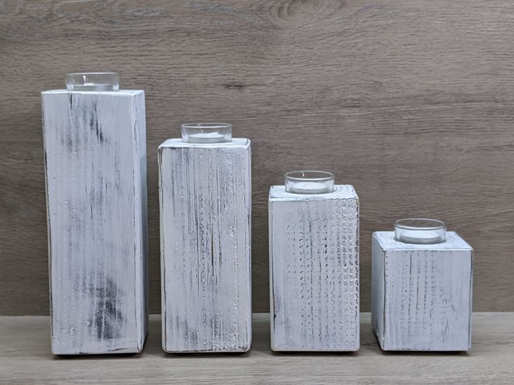 three white vases sitting next to each other on a wooden table with wood background