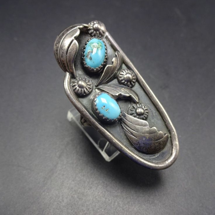 "VINTAGE NAVAJO RING DESCRIPTION: This fabulous old ring features a pair of high blue turquoise cabochons. The gemstones are secure in sawtooth bezel, on a foundation of heavy gauge vintage sterling silver. Applied leaves and hand stamped raindrops embellish the face of the ring. This ring will be a treasured addition to your collection of fine vintage Native American jewelry. MEASUREMENTS: Ring face measures 1 7/8\" x 7/8\" RING SIZE: 6 1/2 WEIGHT: 11.9 grams SIGNED: Mary Matt (Navajo) and AT s Vintage Oval Turquoise Ring Hallmarked, Vintage Hallmarked Turquoise Ring, Vintage Blue Cabochon Ring, Vintage Hallmarked Turquoise Ring For Collectors, Vintage Hallmarked Turquoise Ring For Anniversary, Vintage Oval Turquoise Cabochon Ring, Vintage Blue Turquoise Ring For Anniversary, Vintage Blue Cabochon Turquoise Ring, Vintage Oval Cabochon Turquoise Ring