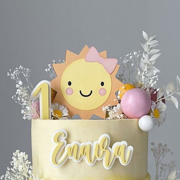 a birthday cake decorated with flowers and an animal topper for the number one on it