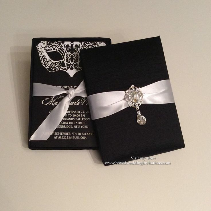 a black and white wedding card with a silver brooch