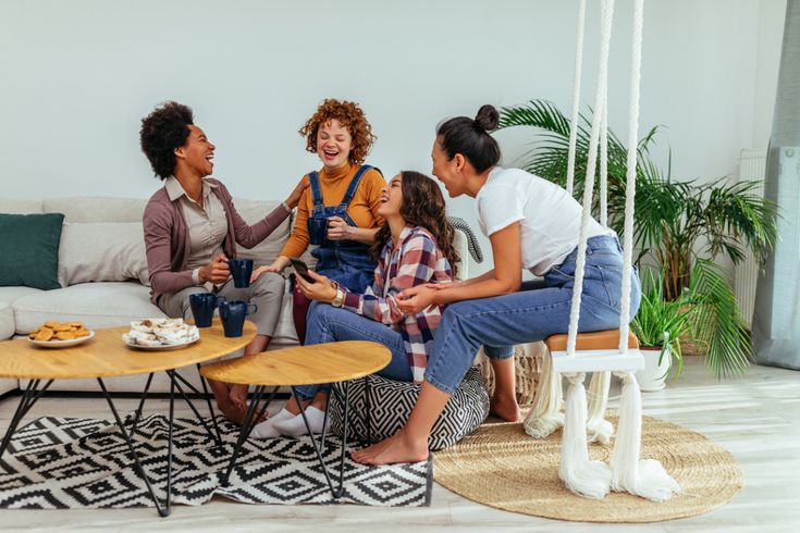 a group of people sitting around a living room table with plates of food on it