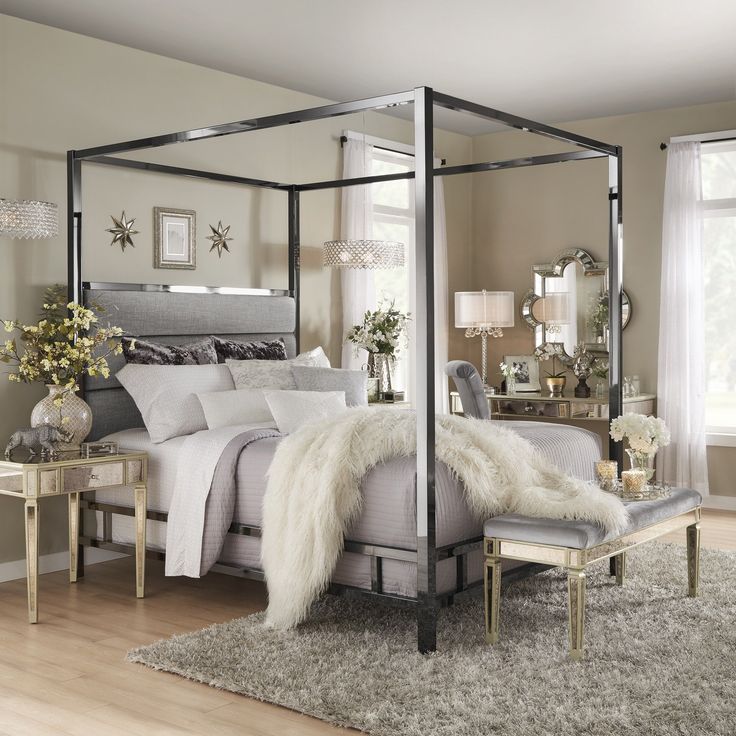 a bedroom with a four poster bed and white fur rugs