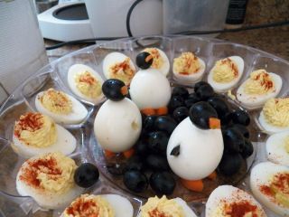 deviled eggs with blackberries and orange peels are arranged on a clear platter