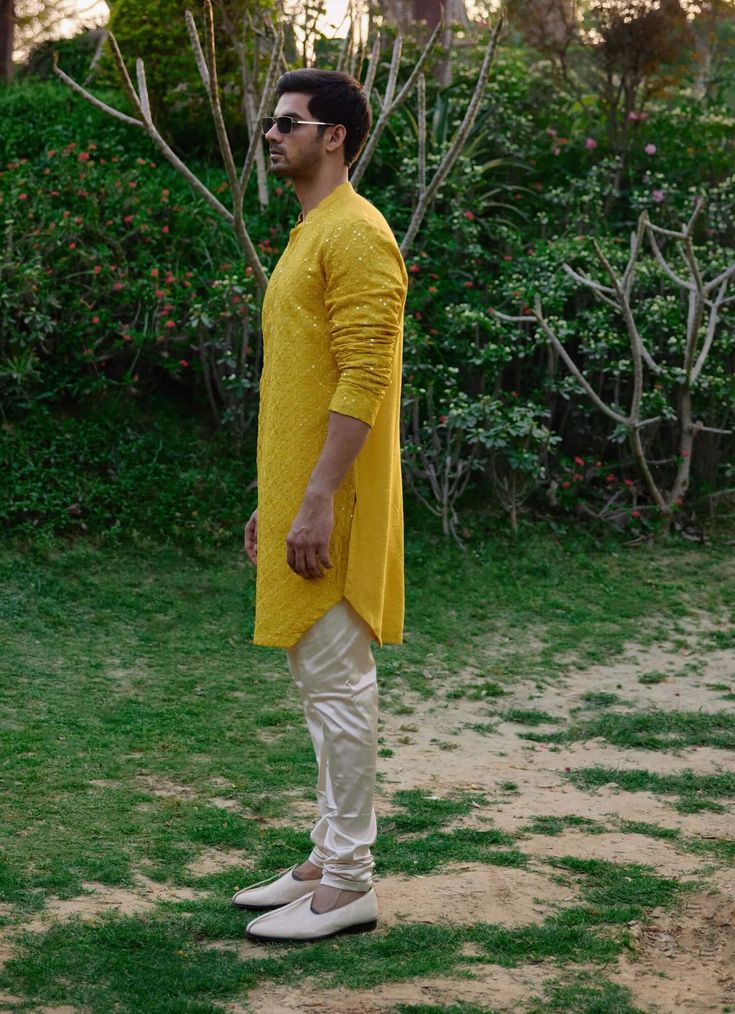 The dholpur kurta in mustard is a sophisticated choice for Indian grooms, perfect for haldi, mehndi, or sangeet ceremonies. Crafted from a blend of viscose cotton silk and georgette, this kurta offers a smooth and breathable feel, ensuring comfort during festive occasions. The kurta comes with an ivory churidaar, creating a balanced and harmonious ensemble. The dholpur kurta is ideal for grooms seeking a classic yet contemporary outfit. Pair it with traditional juttis or modern footwear for a polished and sophisticated appearance. Yellow Chanderi Sherwani Straight Kurta, Yellow Bollywood Kurta With Cutdana, Yellow Bollywood Style Kurta With Cutdana, Bollywood Style Yellow Kurta With Cutdana, Yellow Bollywood-style Kurta With Cutdana, Yellow Sherwani With Resham Embroidery In Chanderi, Yellow Chanderi Sherwani With Resham Embroidery, Transitional Yellow Churidar With Zari Work, Semi-stitched Yellow Kurta For Transitional Season