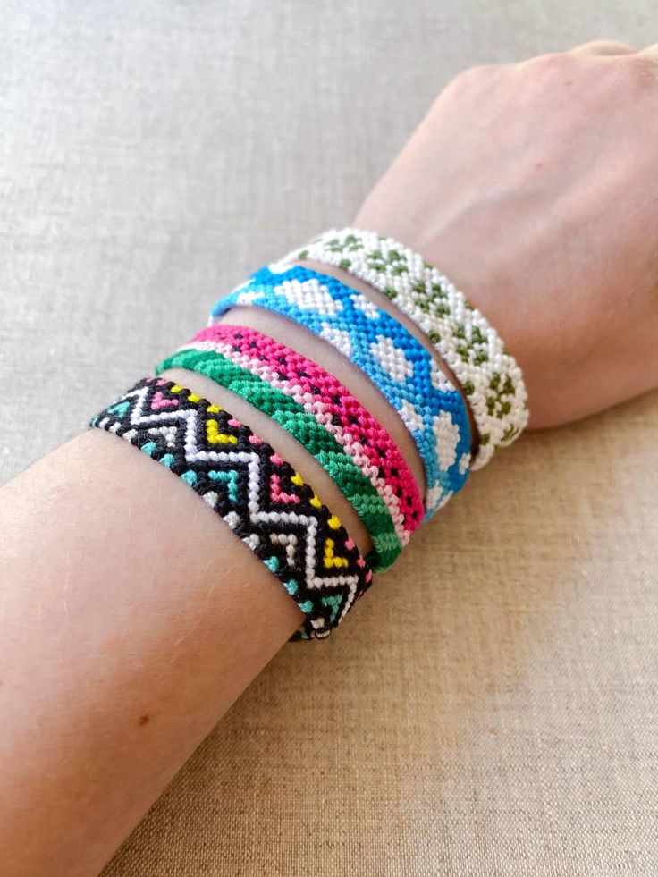 a woman's arm with four bracelets on it, one is multicolored