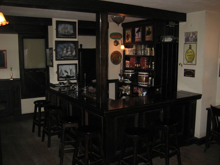 a bar with several stools around it and pictures on the wall behind it,