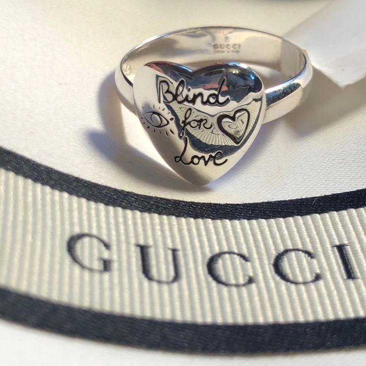 New With Tags. Gucci Box, Pouch & Papers. Gucci Ring. Band Ring In Sterling Silver. Graphic Engraved With Symbolic Gucci Motifs. Heart Shaped Face. The Front Features Eye, Heart And The Phrase Blind For Love. Bird And Flowers Adorn The Back. Size 7.5. Gucci Sterling Silver Ring For Formal Occasions, Gucci Silver Ring With Polished Finish, Gucci Sterling Silver Ring, Gucci Luxury Silver Rings, Luxury Silver Gucci Rings, Gucci Sterling Silver Anniversary Jewelry, Gucci Silver Sterling Silver Rings, Gucci Sterling Silver Jewelry For Anniversary, Classic Gucci Sterling Silver Rings