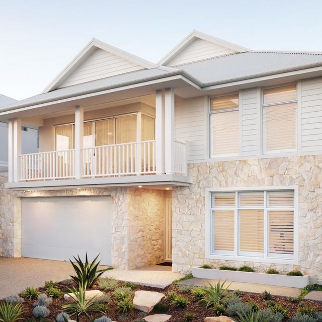 a white two story house with lots of windows and plants in the front yard area