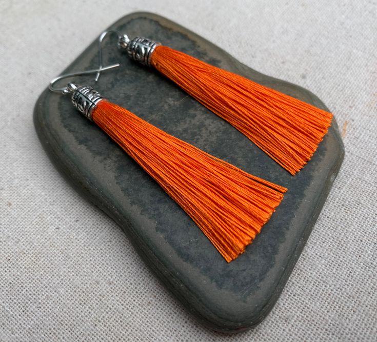 "Chic orange tassel earrings! They would add a pop of color to any outfit for any occasion. Dress them up or down. They are timeless and versatile. They are lightweight, fun and unique! The tassels measure 2 1/8\" long by 1/4\" wide. They hang from simple silver ear wire hooks. Overall drop length is about 2 1/4\". Metal is allergy free plated silver. These are my latest creation! I have them available in many colors! Find them all under the category tassel earrings in my shop. Thanks for stoppi Lover Earrings, Autumn Earrings, Orange Jewelry, Boho Hoop Earrings, Silver Chandelier Earrings, Boho Hippie Chic, Orange Earrings, Fall Earrings, Unique Jewelry Designs