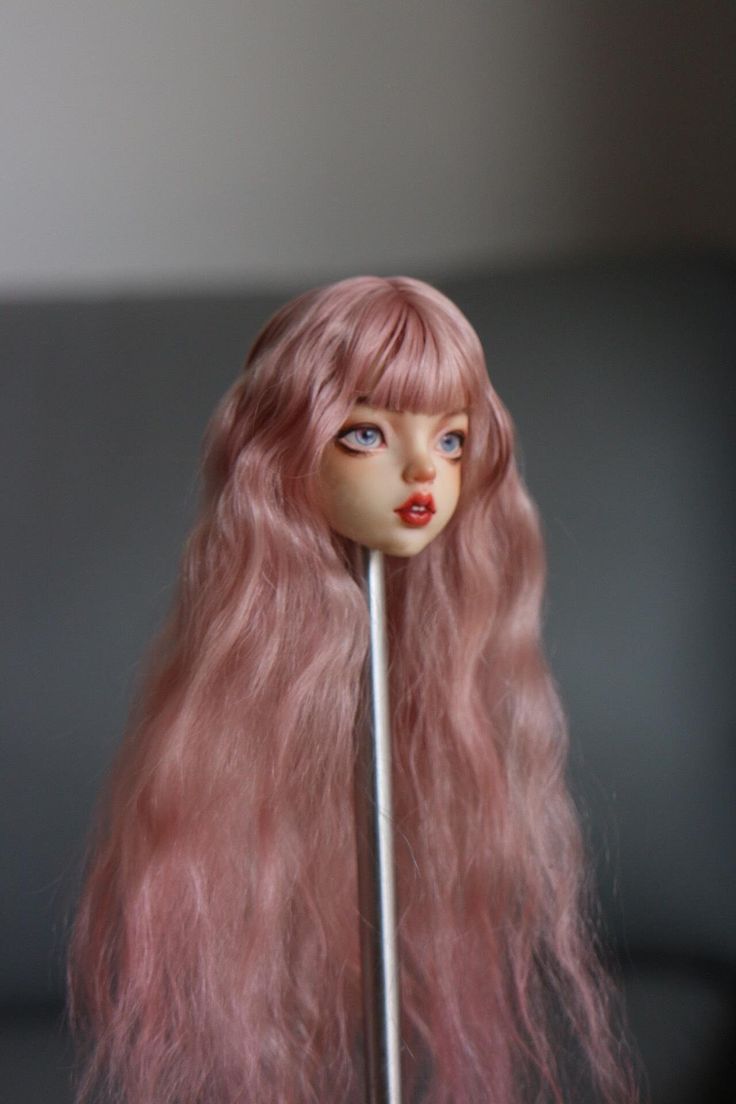 a doll with long pink hair holding a stick