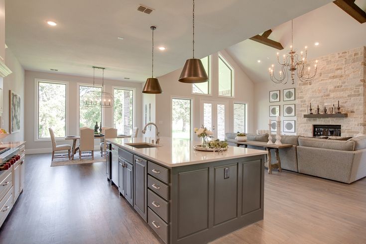 a large open concept kitchen and living room in a house with wood floors, white walls, and windows