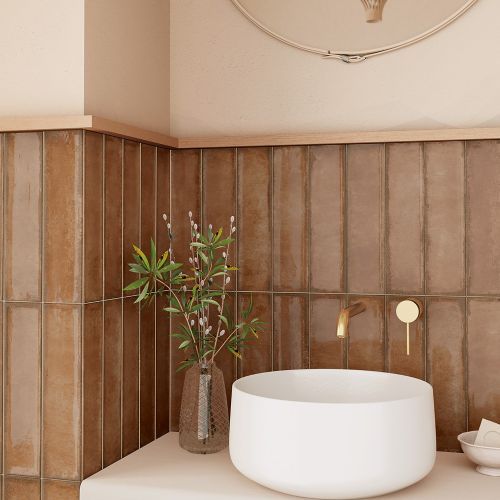 a white sink sitting next to a brown tiled wall