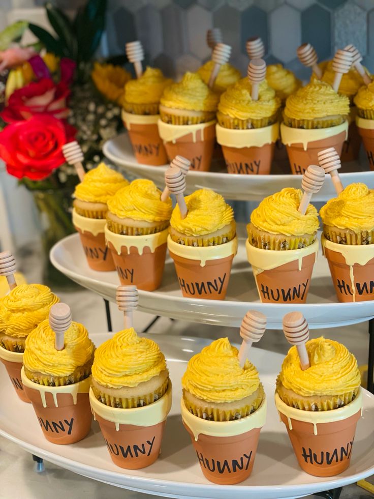 several cupcakes are arranged on three tiered plates with honeycomb toppers