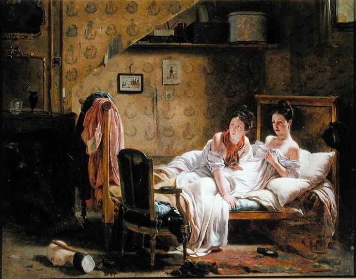 two women sitting on a bed in a room