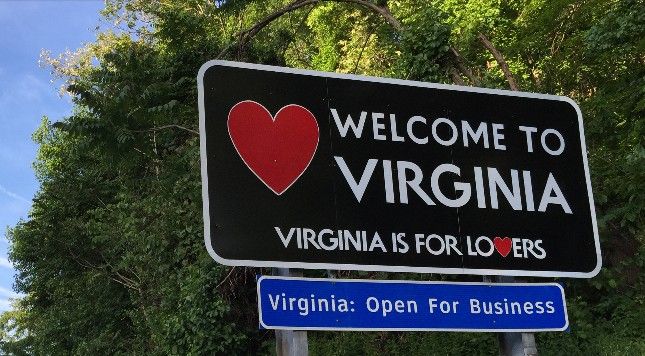 a welcome sign to virginia is posted in front of some trees