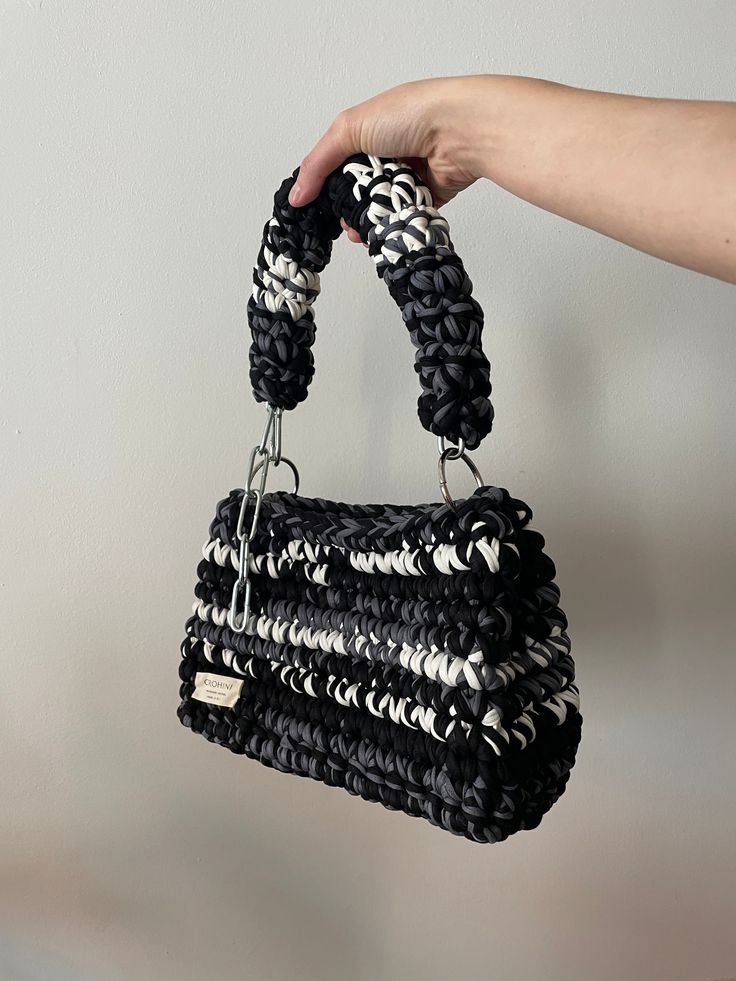 a hand holding a black and white purse