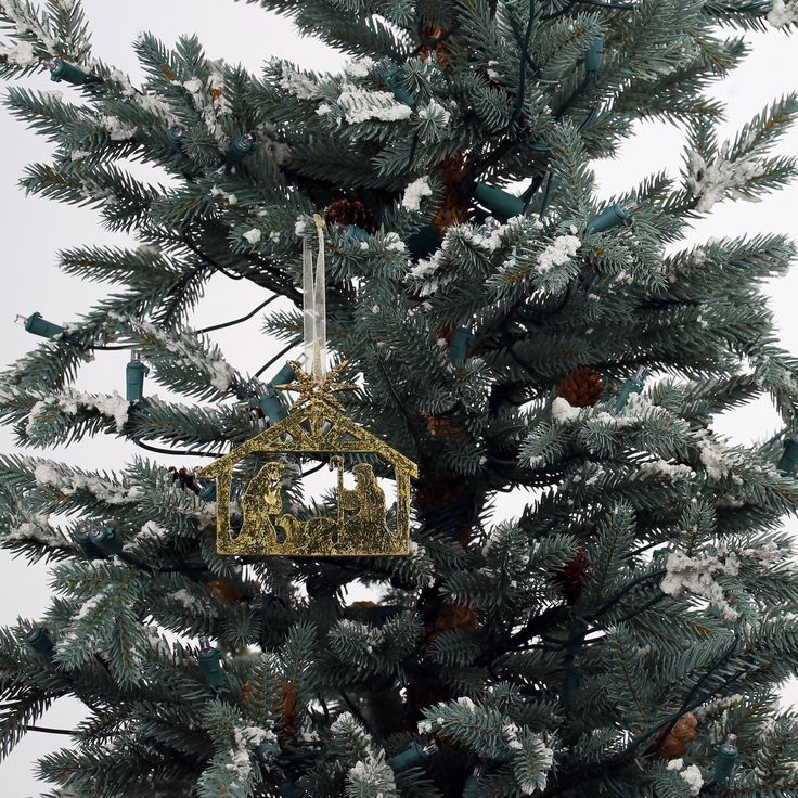 an ornament hanging from the top of a pine tree with snow on it