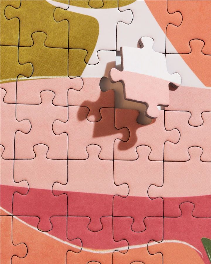 a piece of puzzle sitting on top of a pink and orange floor next to a plant