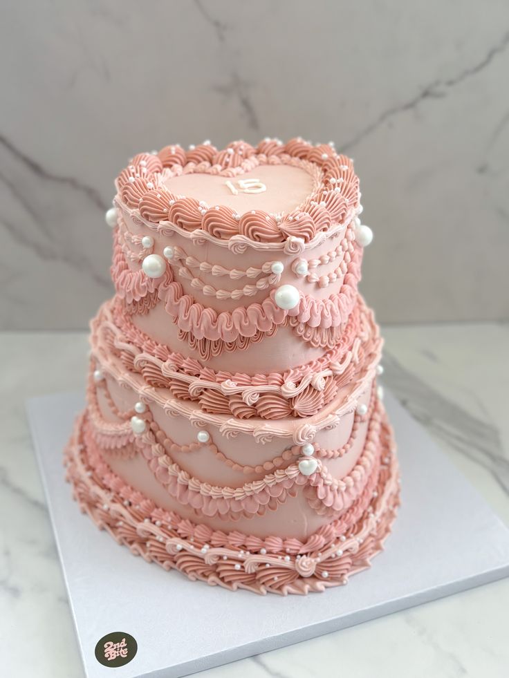 a three tiered cake with pink icing and pearls on it's sides