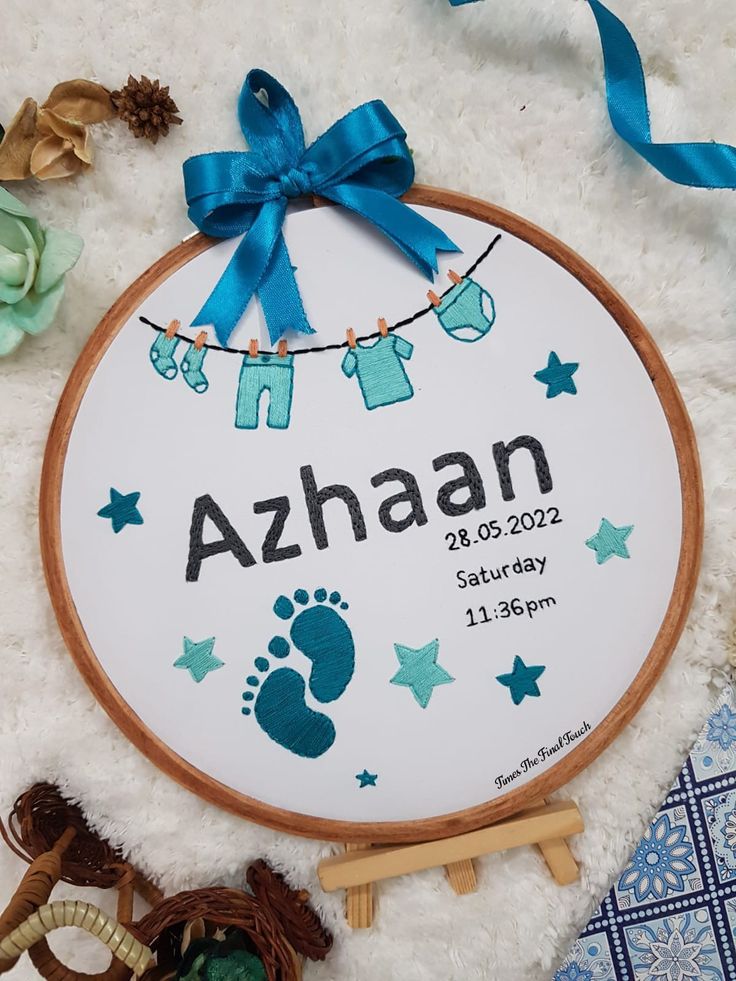 a baby's birth announcement is displayed on a white rug with blue ribbon and decorations