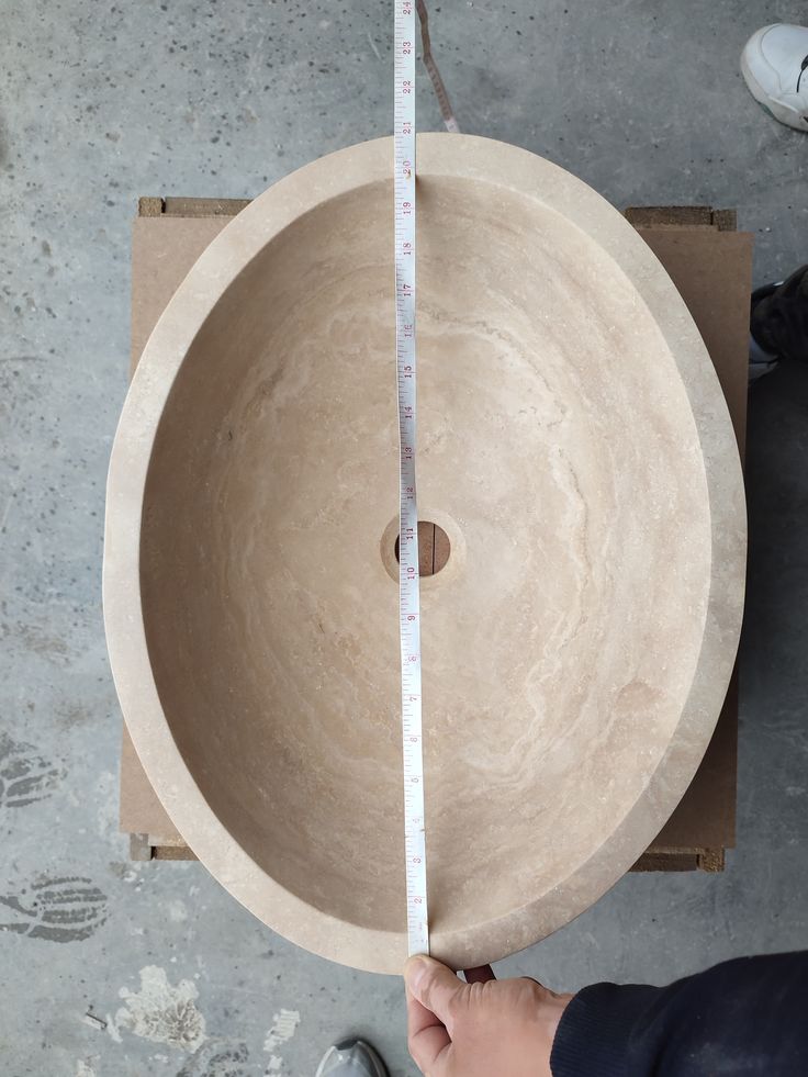 a person is measuring the height of a stone bowl