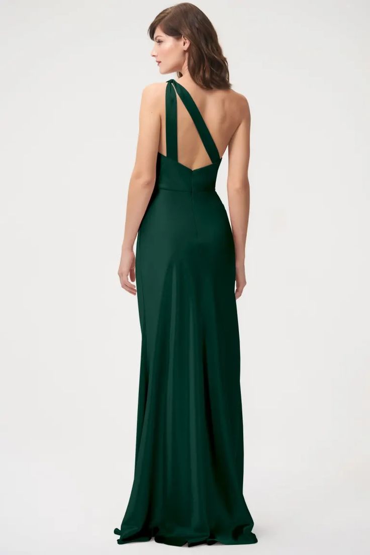 a woman in a long green dress is looking back at the camera and she has her hands on her hips