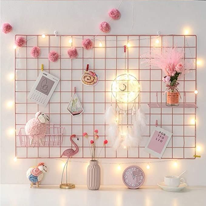 a white table topped with pink decorations and lights next to a wall covered in pictures