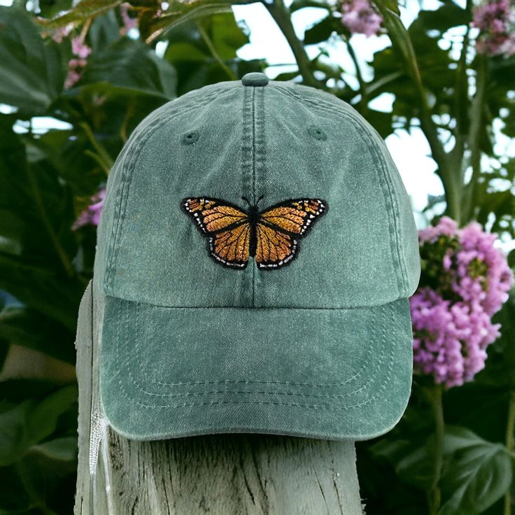 Monarch Butterfly embroidered on a pigment dyed cap in choice of color. Shown on forest   Colors may not look the same on all monitors Adams brand 100% garment-washed cotton twill 6-panel, unstructured, low-profile tuck-away back leather strap with antiqued brass buckle and grommet adjustable.  fits most men and women Cool-Crown™ mesh lining four rows of stitching on bill Garment washed, pigment dyed gives the cap a nice faded look Caps made in china-embroidery done in USA Spring Outdoor Washed Hat, Spring Outdoor Snapback Dad Hat, Snapback Dad Hat For Outdoor Use In Spring, Spring Soft-washed Curved Bill Hats, Green Baseball Cap For Spring Outdoor Activities, Green Baseball Cap For Outdoor Spring Activities, Green Dad Hat For Outdoor Spring Activities, Spring Outdoor Dad Hat With Curved Brim, Spring Outdoor Dad Hat With Curved Visor