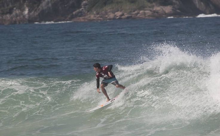 a man riding a surfboard on top of a wave in the ocean with an island in the background