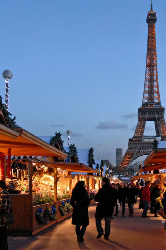 the eiffel tower is lit up at night, with people walking around it