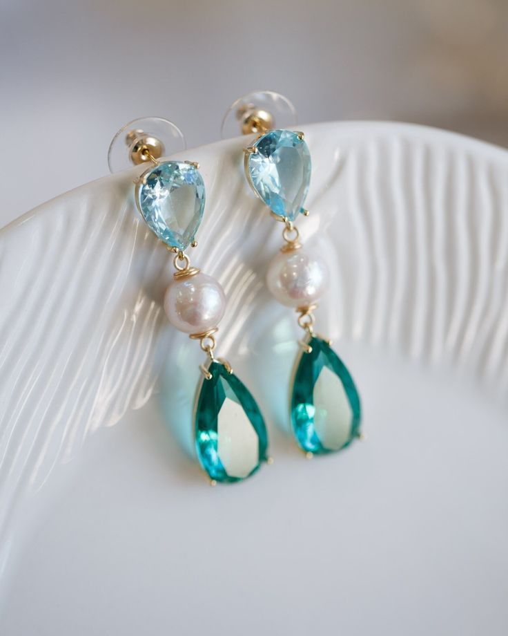 Adorned with vivid emerald and sky-blue cubic stones and featuring a freshwater pearl drop, these exquisite Elina Blue Cubic Pearl Earrings will make a sophisticated statement on any occasion - be it for day-to-day exploring, special events, or gifting a special someone. As part of the Artisan Made collection, this particular piece is one-of-a-kind - making it even more special and desirable. Follow me on Instagram: @cubic_jewels Elegant Light Blue Drop Jewelry, Turquoise Pearl Drop Earrings, Elegant Turquoise Pearl Drop Earrings, Blue Gemstone Pearl Drop Earrings, Blue Teardrop Pearl Earrings With Gemstone, Elegant May Birthstone Blue Jewelry, Wedding Jewelry Earrings, Cluster Earrings, Pearl Drop