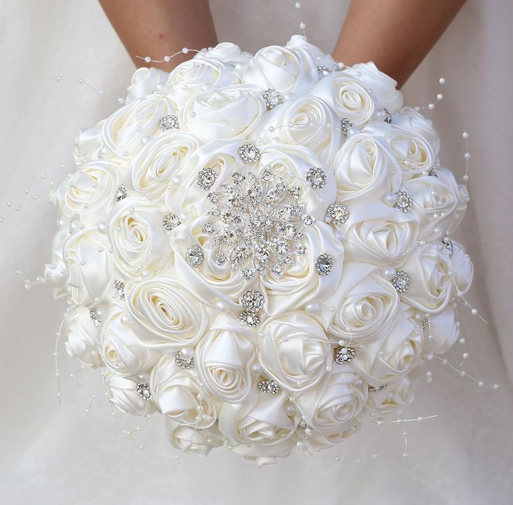 the bride's bouquet is made up of white roses and crystal brooches