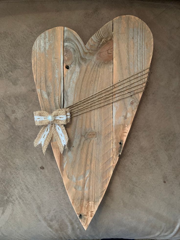 a wooden heart hanging on the side of a couch with a string tied to it