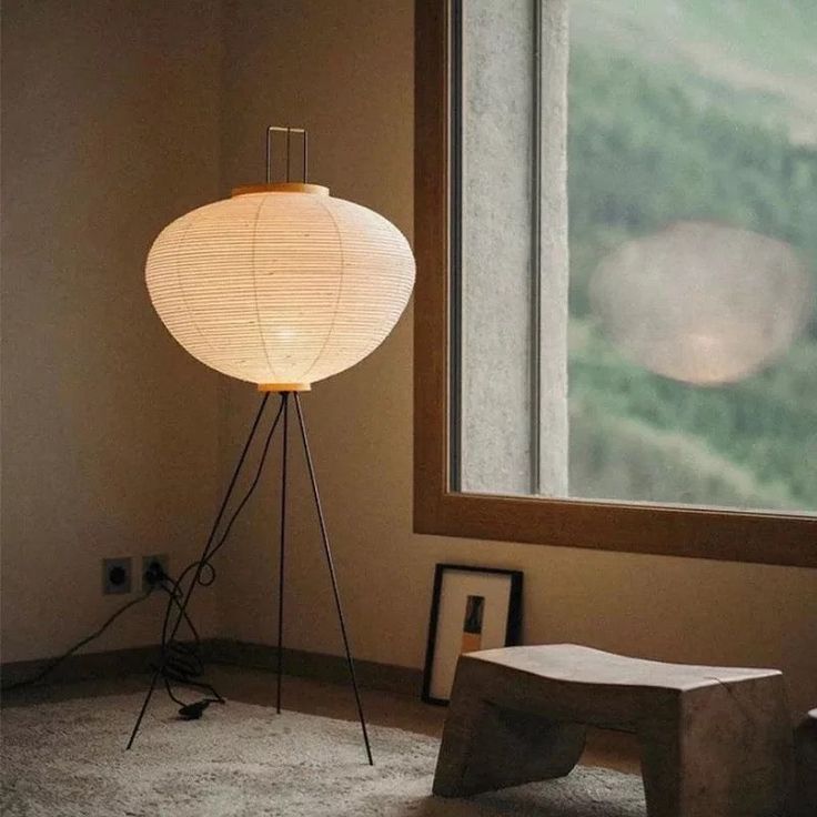 a floor lamp sitting next to a window in a room with a mountain view behind it