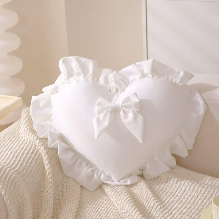 a white heart shaped pillow sitting on top of a bed