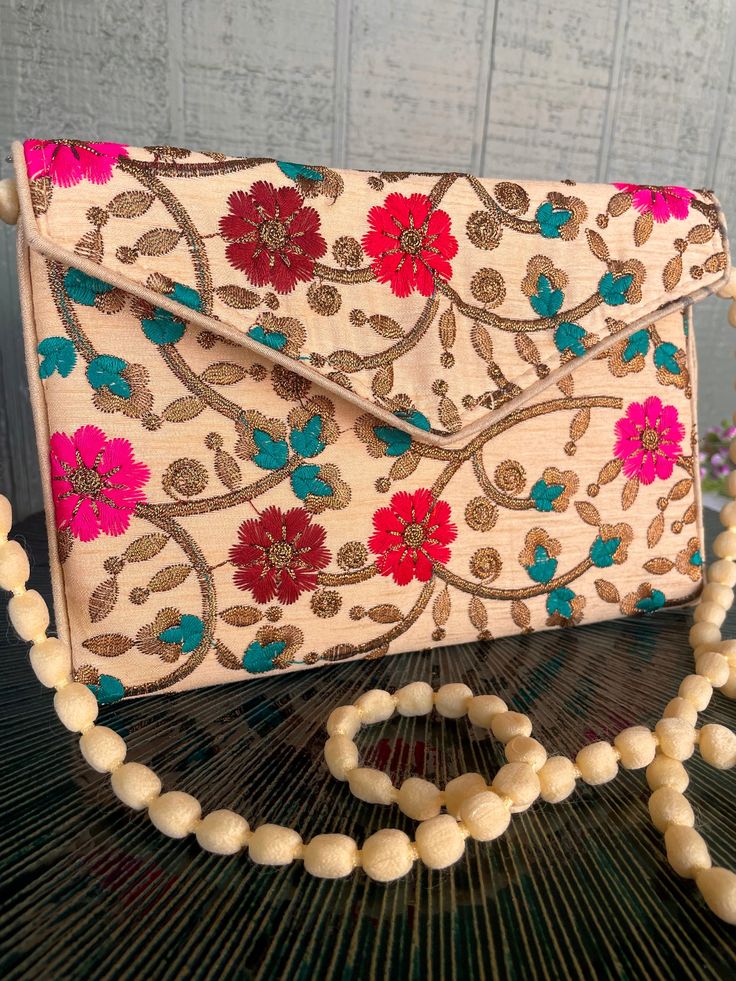 "This a beautiful handmade versatile purse with a magnetic closure from India. It can be worn over the shoulder, across the body. The strap may be tucked inside to be worn as a clutch. The floral pattern spans both the front and back. It would make a lovely statement piece to accent any outfit.  Clutch Bags, Indian Wedding Gifts, Wedding favor, Gift Party Handbag, Indian Clutches, Gift for Her, Gift for Mom. 9.5\" Length x  29.5\" Height (from Bottom to top of handle) x 6.5\" Width Thank you for visiting BONNET VINTAGE!  Please check out my other listings for more great finds!  https://www.etsy.com/shop/BonnetVintage Please like and share our page. Thank you." Festive Beige Pouch Shoulder Bag, Handmade Beige Bags For Festive Occasions, Festive Rectangular Bag With Floral Embroidery, Envelope-shaped Box Bag As A Gift, Embroidered Shoulder Bag Clutch, Elegant Shoulder Bag With Multicolor Embroidery, Traditional Floral Embroidered Clutch For Everyday, Traditional Floral Embroidery Clutch For Everyday, Festive Beige Rectangular Shoulder Bag