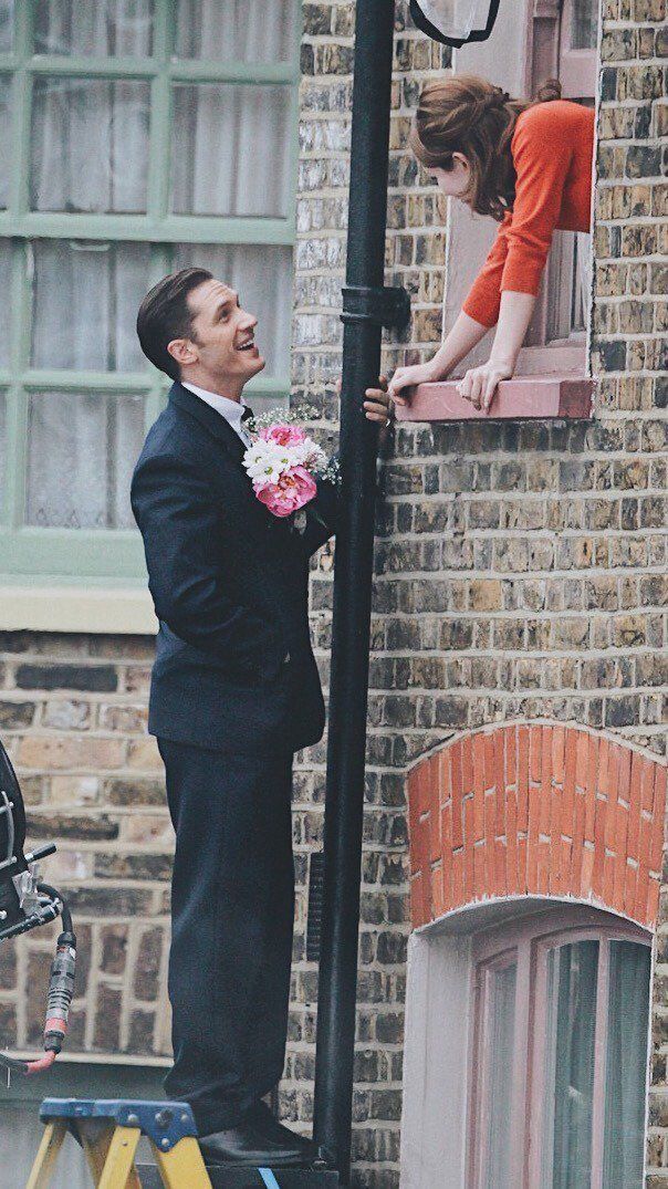 a man standing next to a woman on top of a street light near a brick building