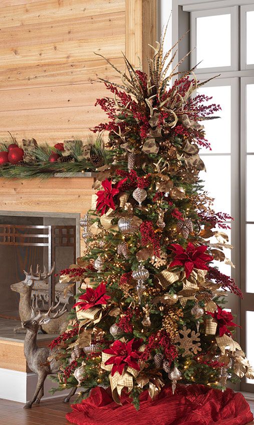 a decorated christmas tree in front of a fireplace with red and gold decorations on it