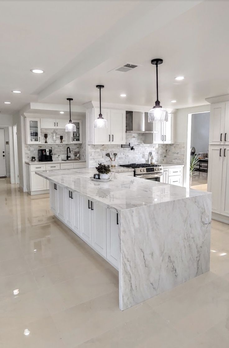 a large kitchen with marble counter tops and white cabinets, along with an island in the middle