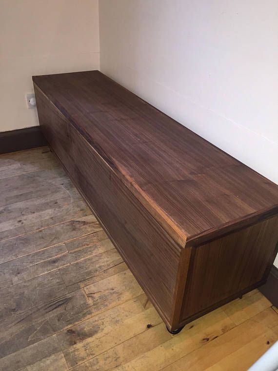 a wooden bench sitting on top of a hard wood floor next to a white wall