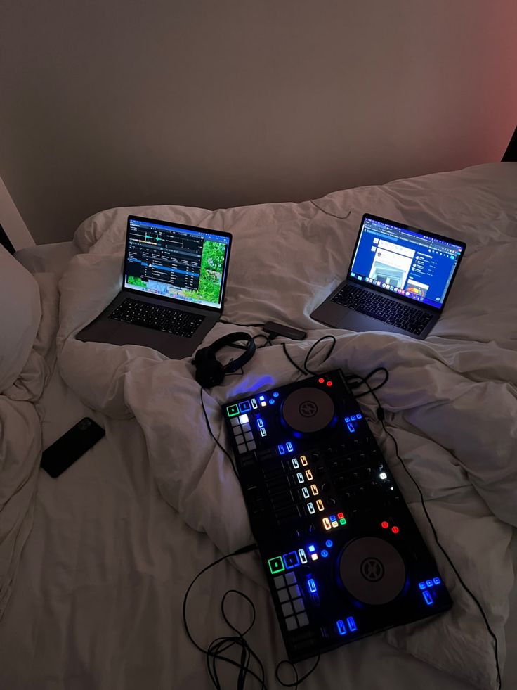 two laptops sitting on top of a bed next to each other