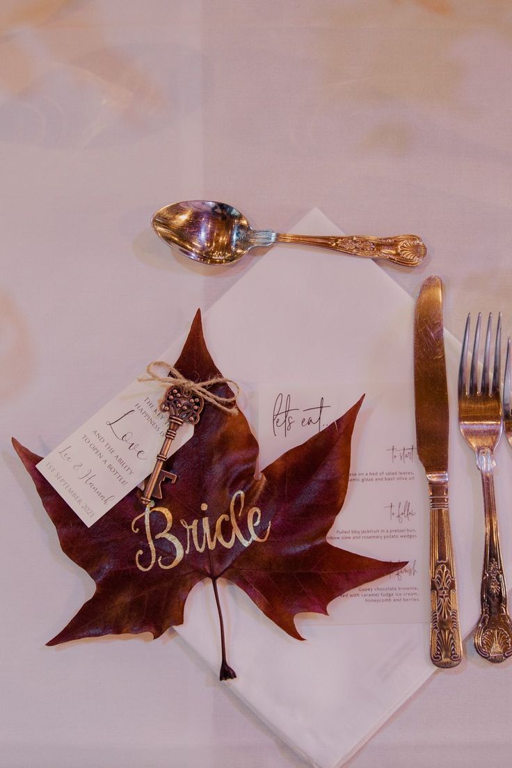 a place setting with silverware, napkins and a maple leaf on the table