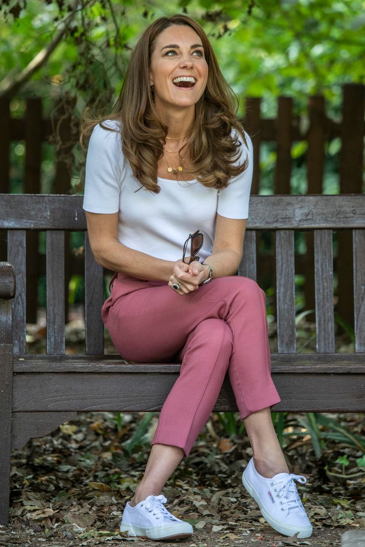 a woman sitting on top of a wooden bench